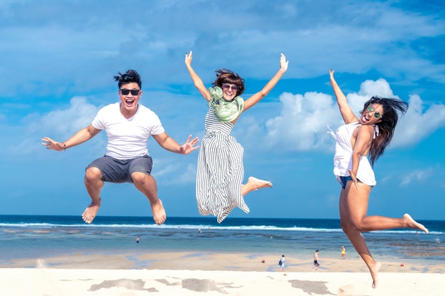 Usmiati ľudia, ktorí skáču na pláži